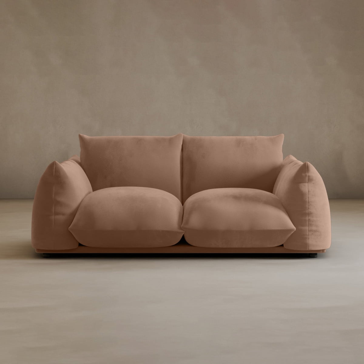 The Calypso Loveseat, a plush modern 2-seater in light brown, features oversized cushioned seats and backrests. It sits against a plain light beige wall on a smooth floor.
