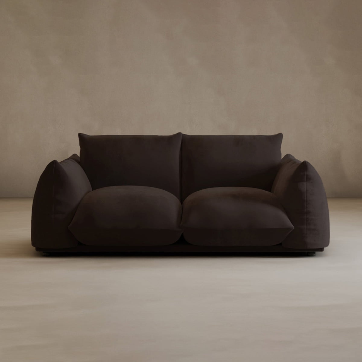 The Calypso Loveseat, a plush dark brown 2-seater with oversized cushions, stands against a beige wall on a light floor, offering minimalist style and cozy modern elegance.