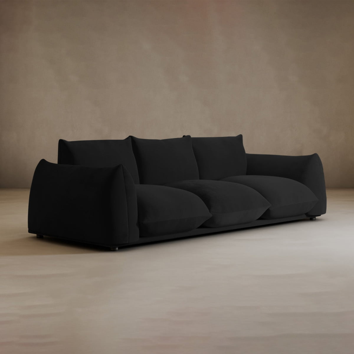 The Calypso Three Seater Sofa, with its plush oversized cushions and sleek lines, is an ideal modern choice for minimalistic living rooms. It looks elegant on a light floor against a plain beige wall.