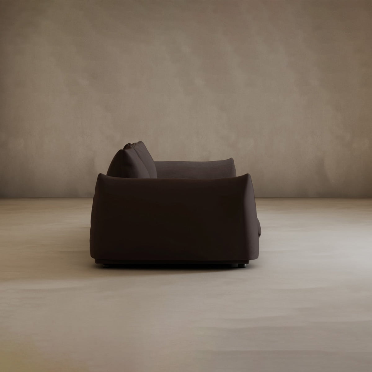 The Calypso Three Seater Sofa in dark brown is shown side-on, set on a light beige floor with a taupe wall—ideal minimalist furniture for a stylish living room.