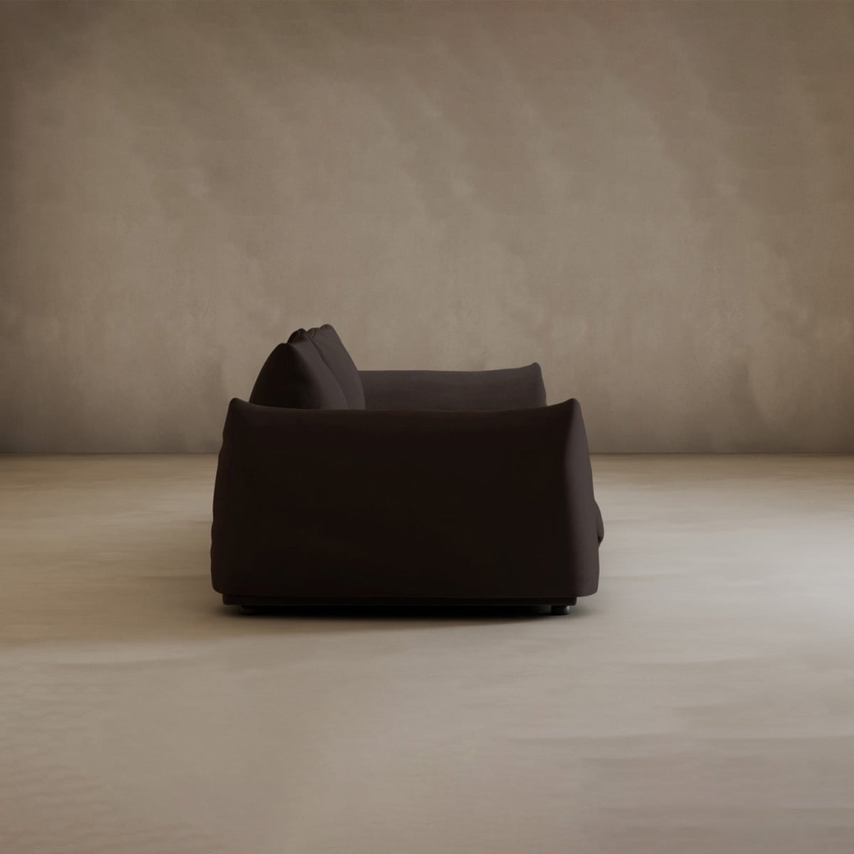 The Calypso Three Seater Sofa, featuring plush cushions, is centered in an empty room with beige walls and a light floor, highlighting its modern and elegant design.