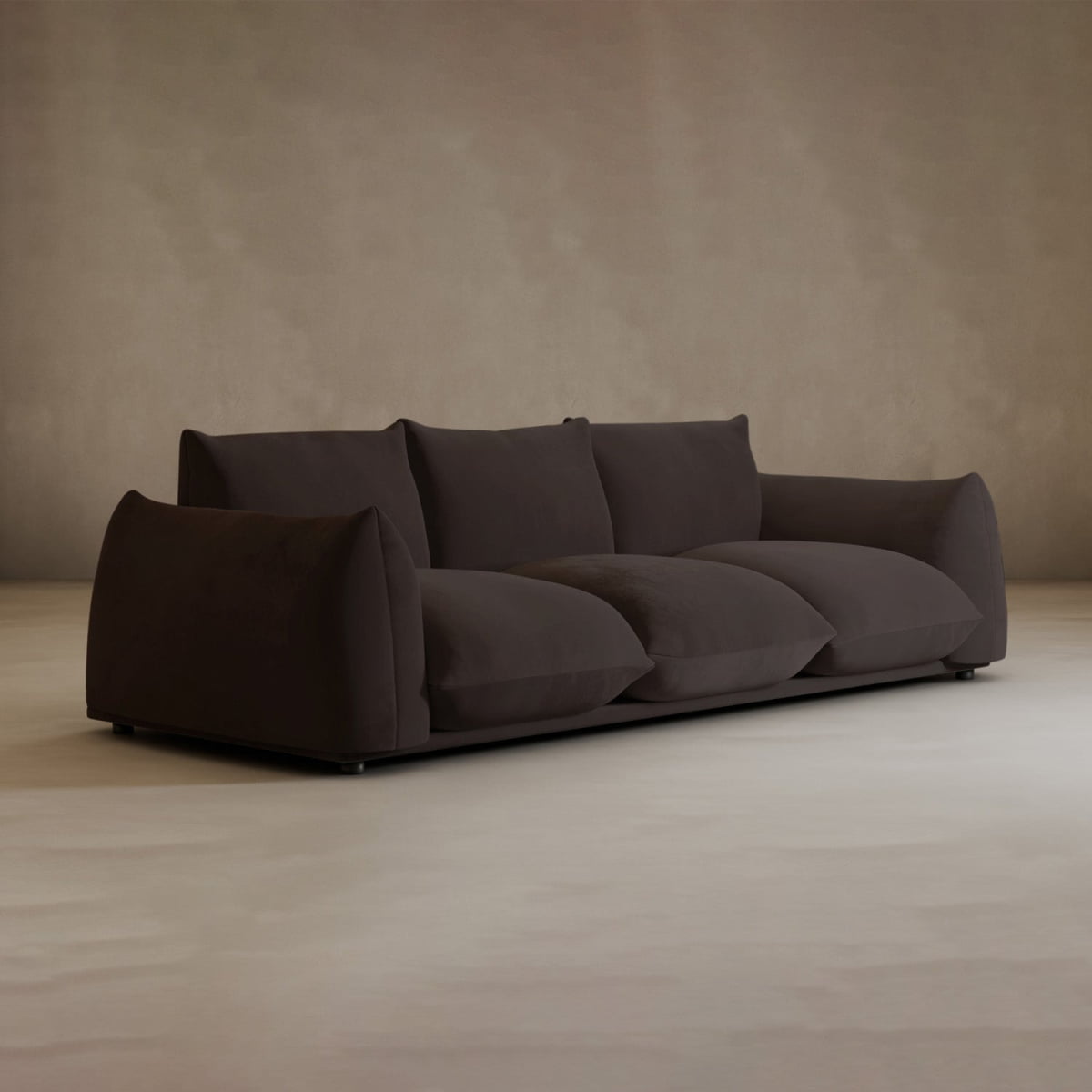 A modern Calypso Three Seater Sofa with wide cushions and low backrests sits in an empty room with beige walls and a light floor—perfect contemporary living room furniture.