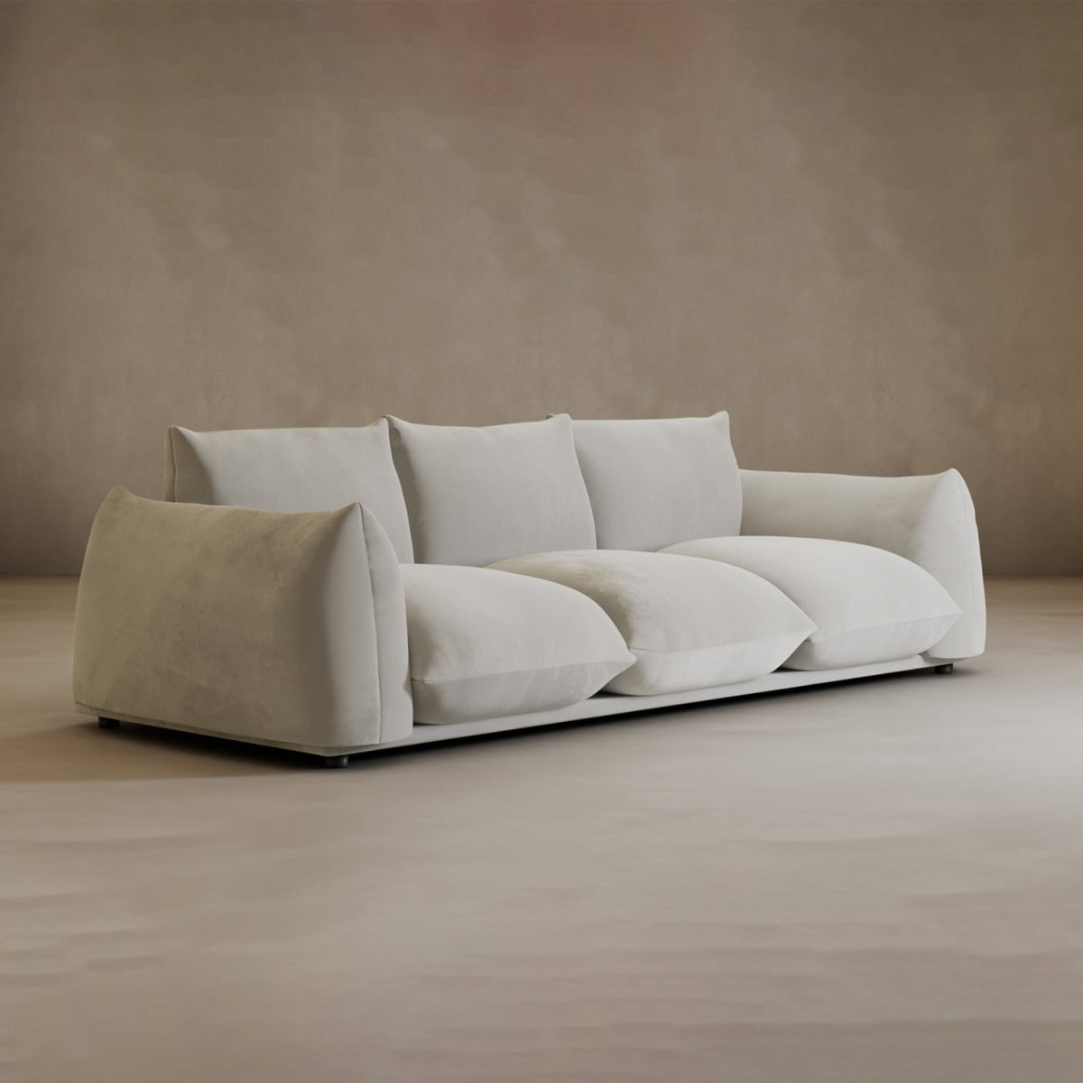 The Calypso Three Seater Sofa, featuring three large seat and back cushions, adds a modern touch to a minimal, neutral-toned room with plain walls and floor.