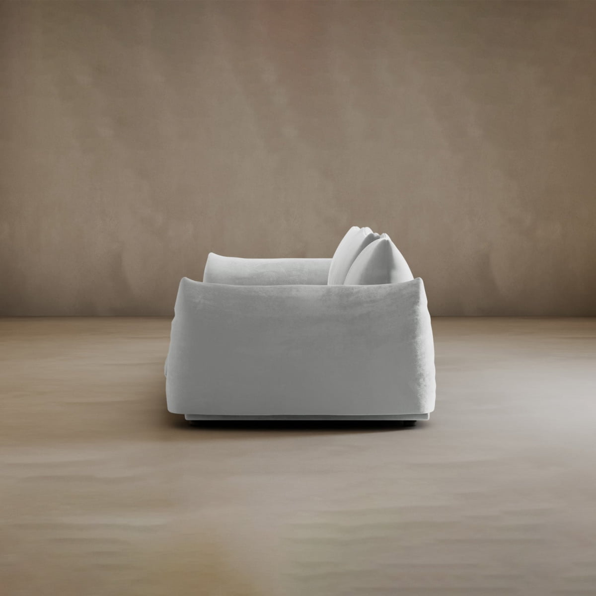 The Calypso Three Seater Sofa, plush and overstuffed in white with two matching cushions, sits at the center of a minimalist room with beige walls and a light floor, offering inviting comfort as stylish modern living room furniture.