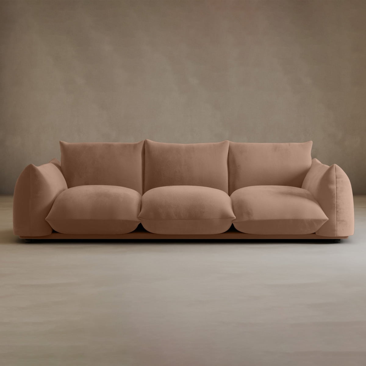 The Calypso Three Seater Sofa features plush light brown cushions and a soft fabric finish, set against a beige wall on a smooth, light floor—an ideal choice for stylish living room furniture.