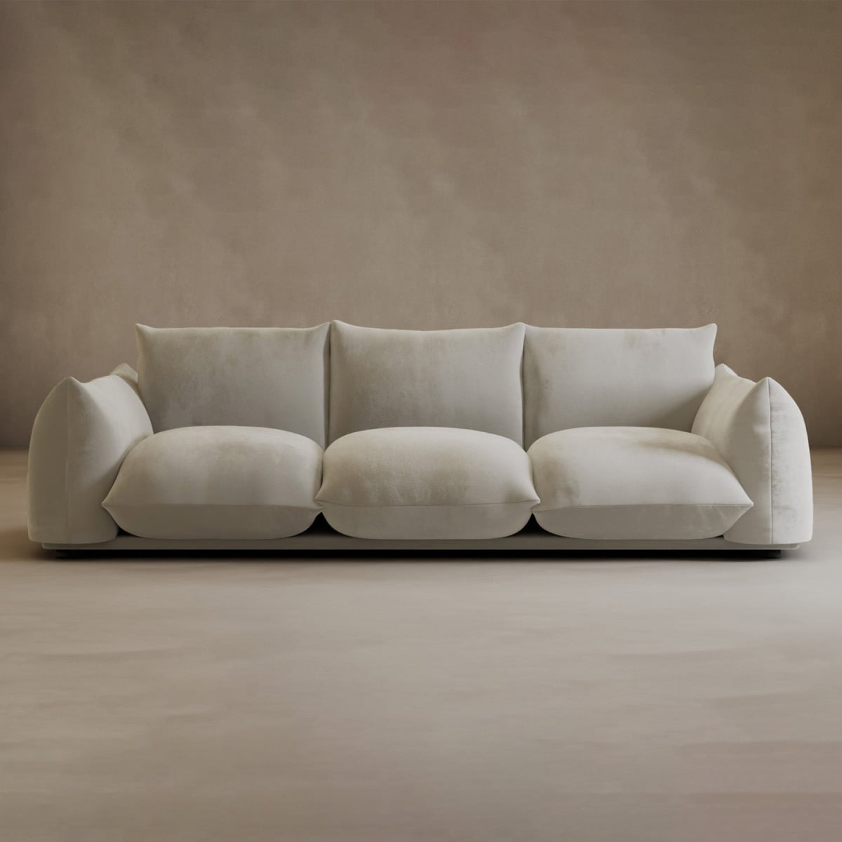 The Calypso Three Seater Sofa, featuring plush white upholstery and oversized cushions, stands in a minimalist room with beige walls and floor, highlighting stylish living room furniture.