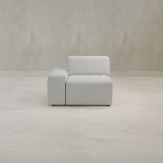 The Canonbury Right Armrest is a modern, light gray armless sofa chair with a right armrest, crafted from high-performance fabric and shown on a smooth, light-colored floor against a matching plain background.