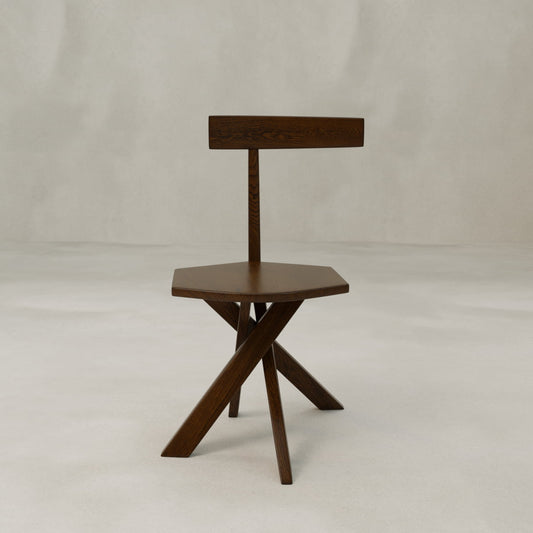 The Cartel Chair features a modern design with bold angles, a pentagonal dark wood seat, three angled legs, and a flat backrest supported by a single post, shown against a plain light background for enhanced sophistication.