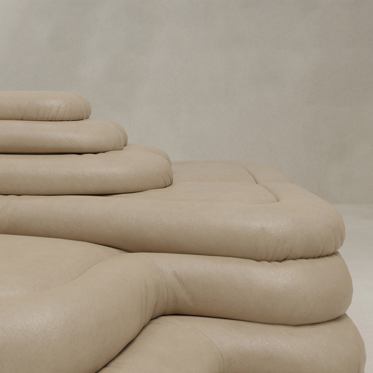 A close-up of the Cascata 2 Piece Sofa Rental shows tiered, beige cushioning with soft, rounded edges against a light textured wall, featuring stacked layers that evoke modern sculptural design.