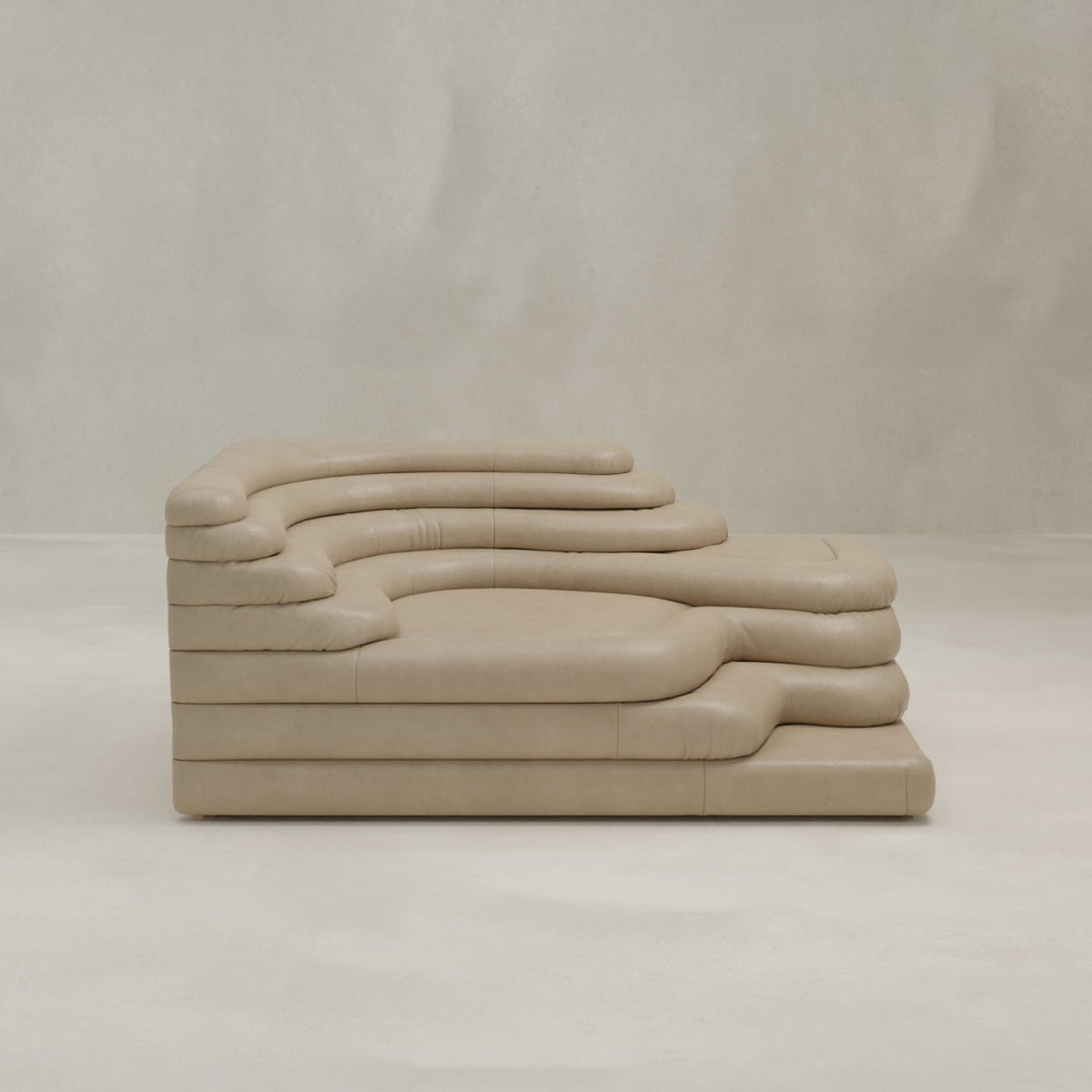 The Cascata Sofa Right Arm is a modern, sculptural beige sofa with layered, rounded cushions and soft, organic curves, shown against a plain light gray background. Its luxurious design resembles stacked, padded forms.