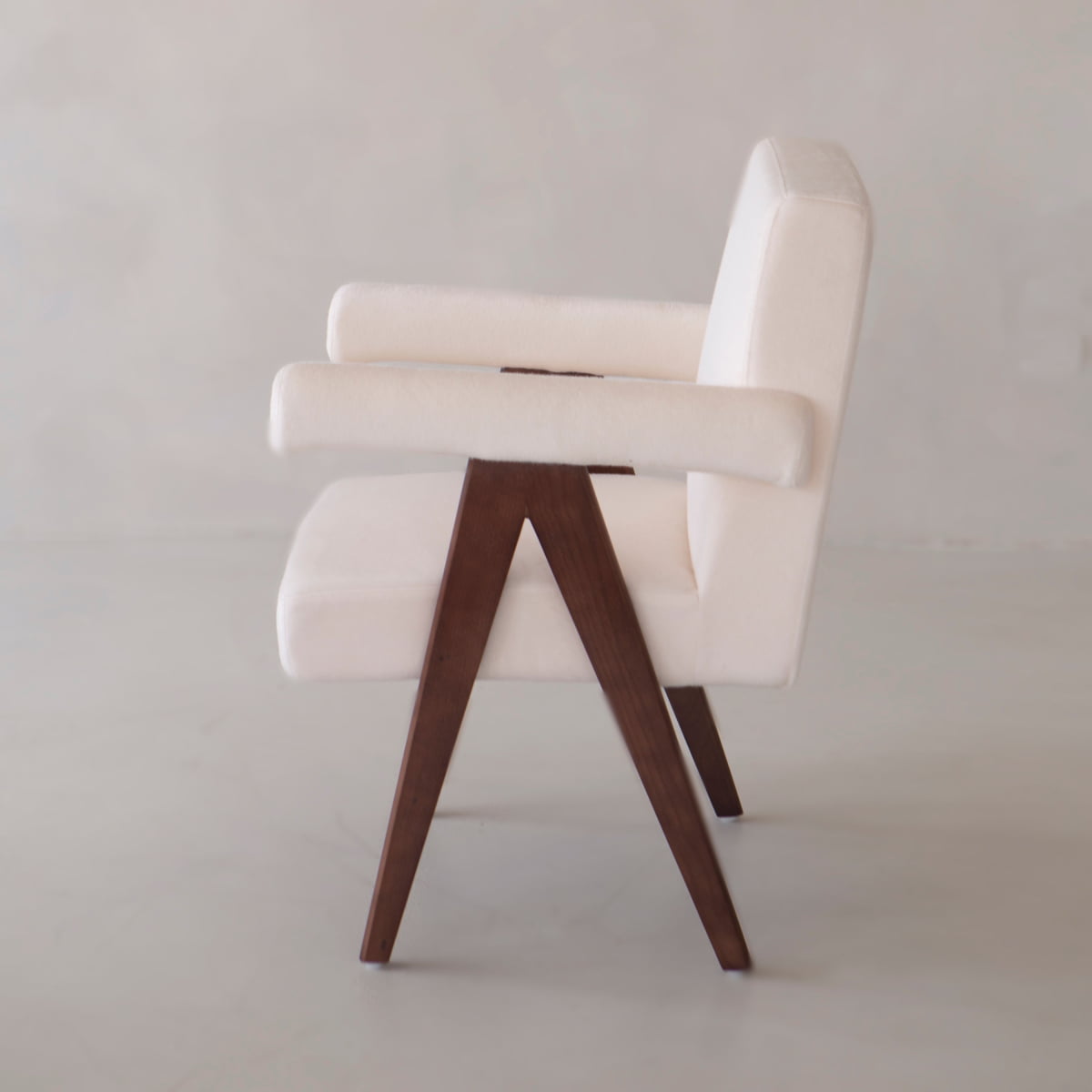 The Chelsea Dining Chair features a comfortable, padded seat with white upholstered cushions and angular wooden legs, shown from the side against a plain light background.