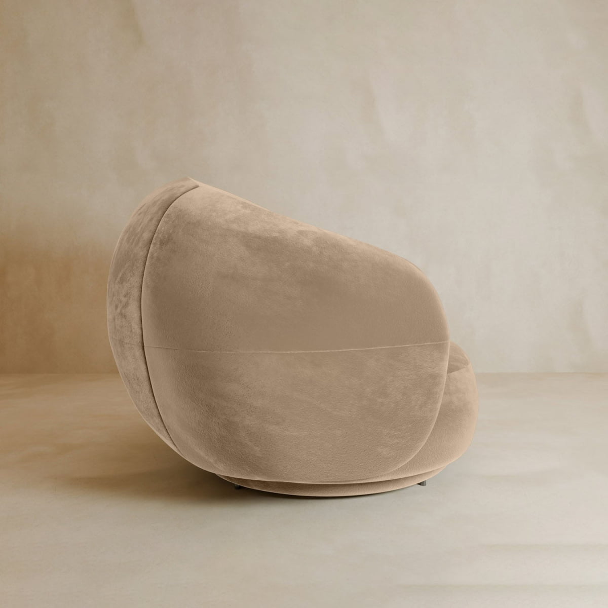 The Clara Armchair, a plush modern beige swivel chair with velvet upholstery and rounded edges, sits on a neutral-toned floor against a matching wall, highlighting its contemporary style.
