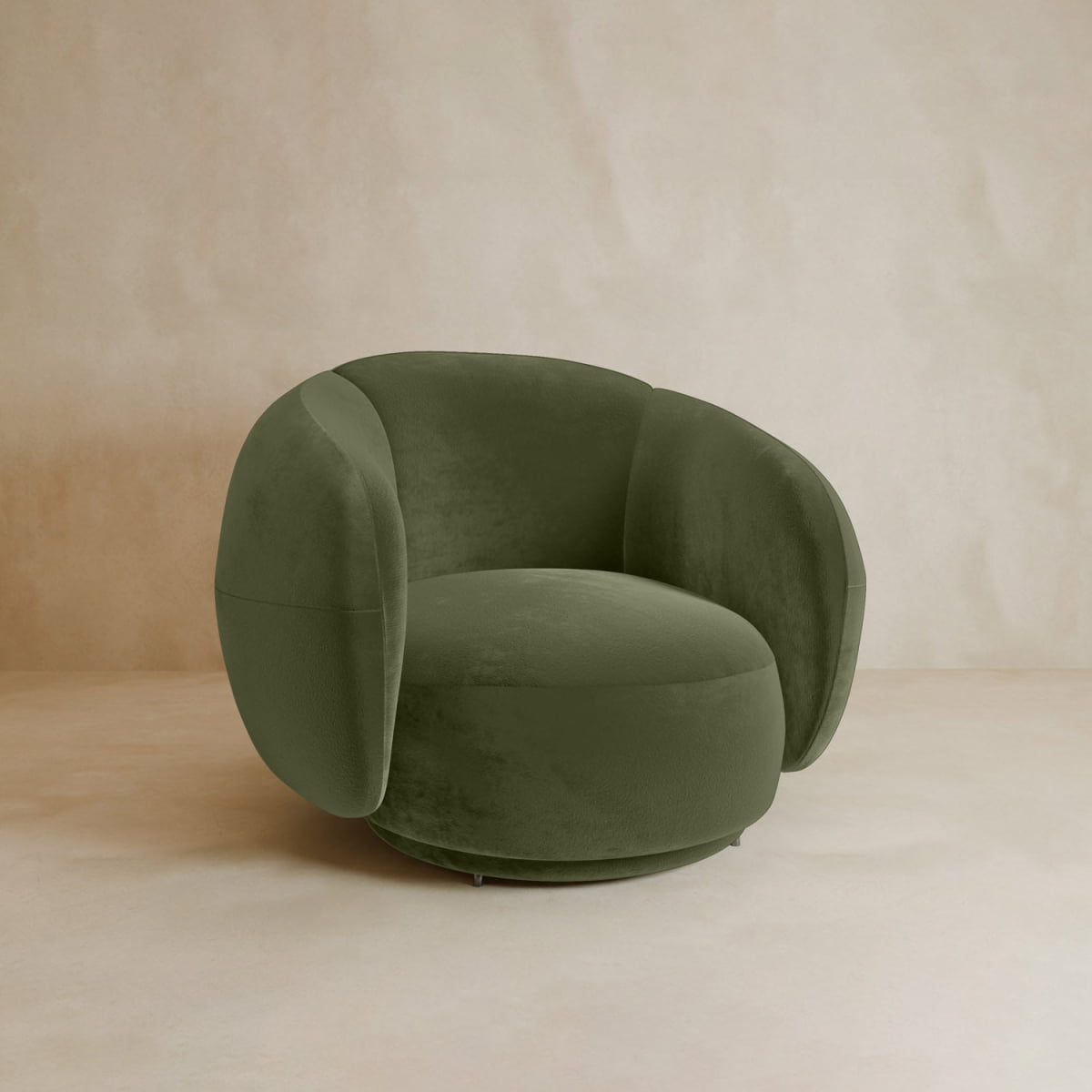 The Clara Armchair features a contemporary olive green velvet design with curved, rounded arms and backrest, set against a light beige floor and matching beige wall.