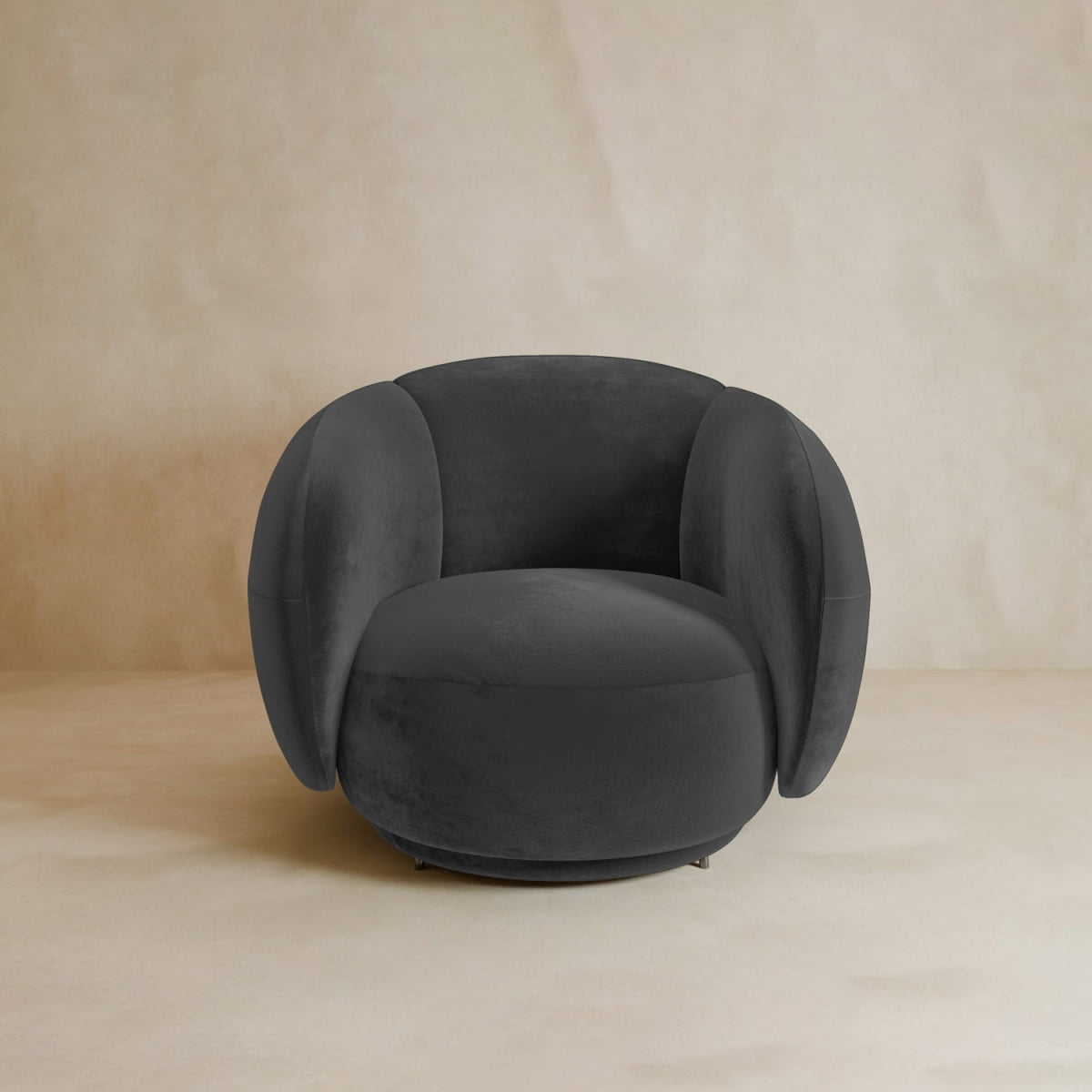 The Clara Armchair boasts a modern plush black velvet design with rounded back and sides, creating a striking contemporary look against any neutral beige backdrop.