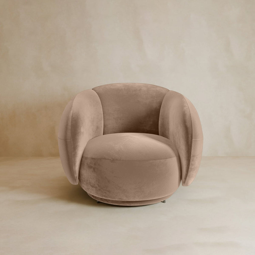 The Clara Armchair offers plush, rounded cushions and modern style in soft beige velvet upholstery, all set on a low circular base for a contemporary look.