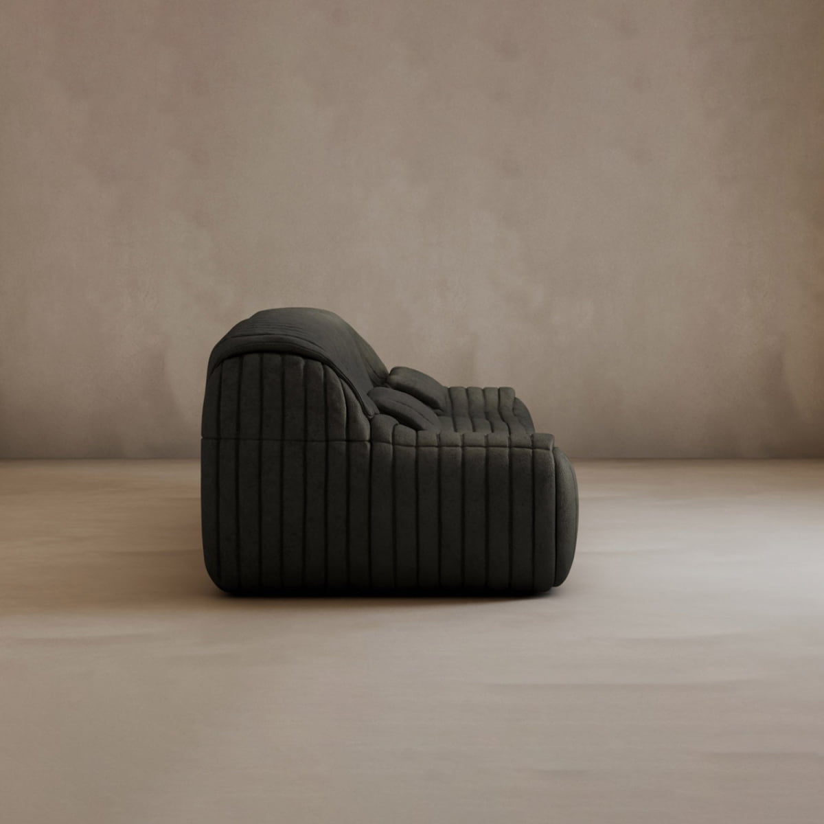 The Calypso Armchair, a modern armless lounge chair with a dark hue and tufted stripe design, sits side-on atop a light floor against a neutral textured wall, highlighting its sleek elegance.