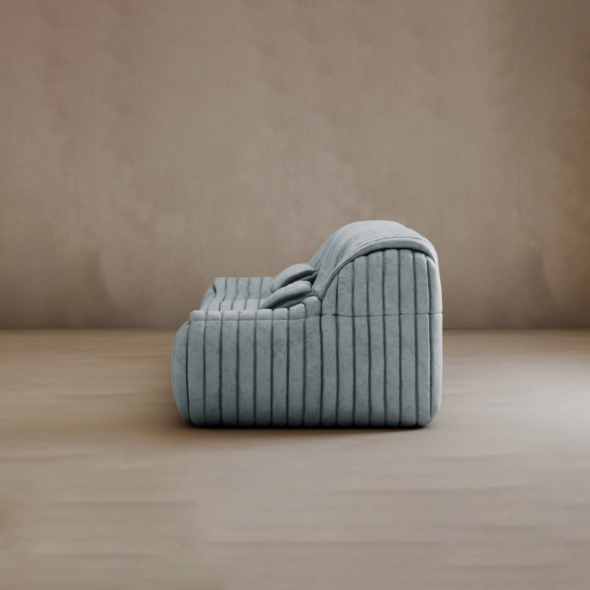 The Calypso Armchair, featuring light gray tufted fabric and a modern low-profile design, is shown from the side on a plain light wood floor against a beige wall.