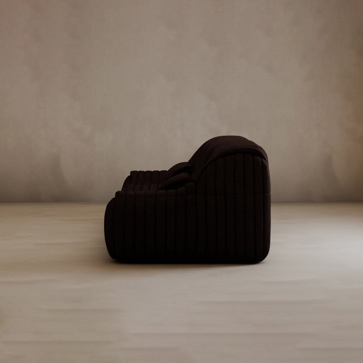 The Calypso Armchair, shown in profile, features a dark, plush textured surface with deep horizontal grooves, embodying modern elegance as it sits on a light floor against a neutral, softly textured wall.