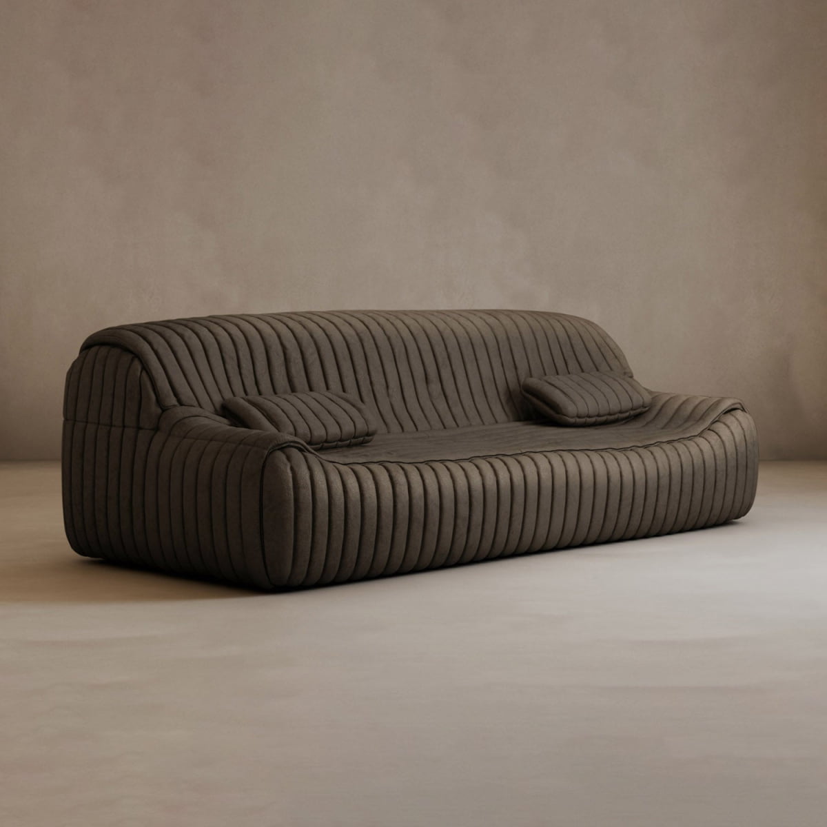 The Calypso Armchair features modern elegance with dark brown fabric, a low backrest, deep seat, and vertical tufted stripe design. Two matching cushions complete the look in this empty room with beige walls and flooring.