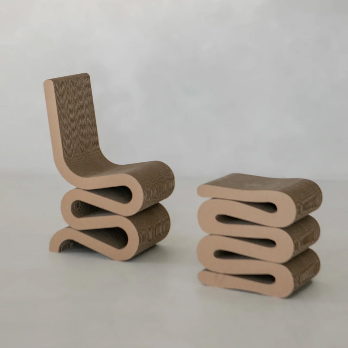 The Curly Wurly Chair and its matching stool feature wavy cardboard layers in neutral brown tones, presented against a plain light background for a contemporary aesthetic.