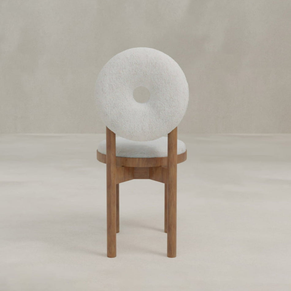 The Nola + Donut Dining Set showcases a modern chair with a circular white backrest featuring a central hole, white upholstered seat, and wooden legs, all set against a minimal neutral background.