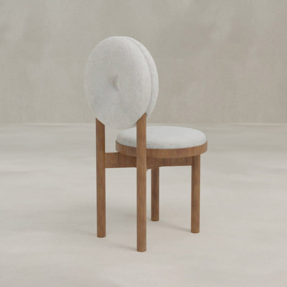 The Nola + Donut Dining Set features a modern chair with a light grey, round cushioned seat and backrest on a simple wooden frame with four straight legs, set against a plain, light background.