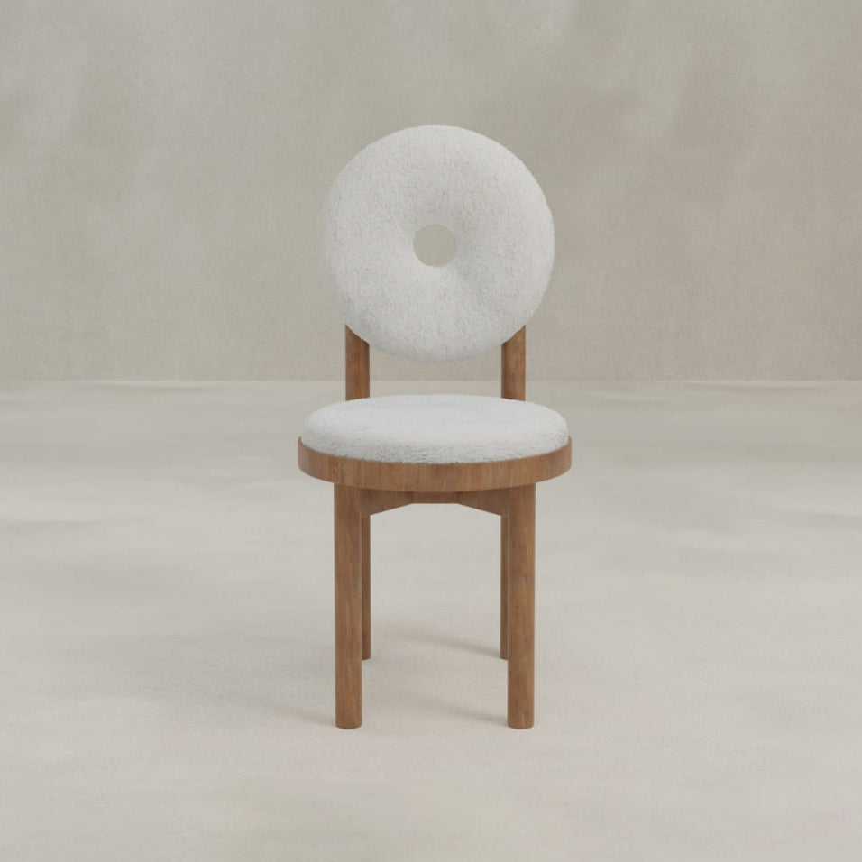 The Nola + Donut Dining Set features a modern chair with a round, white cushioned backrest and central hole, a matching round seat, and wooden legs, all set against a neutral background.