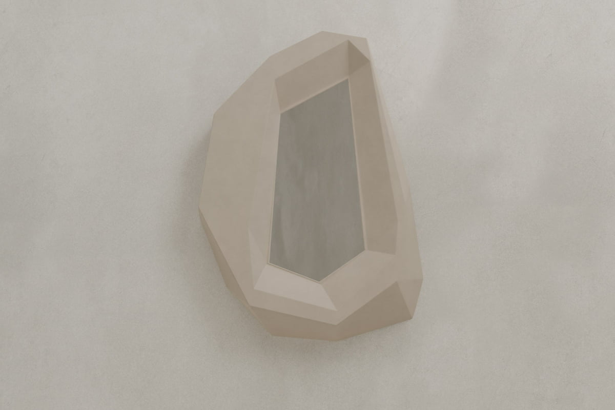 The Facet Mirror Large, featuring a geometric, irregular shape and a beige faceted frame, hangs on a light gray textured wall to bring modern sophistication to the space.