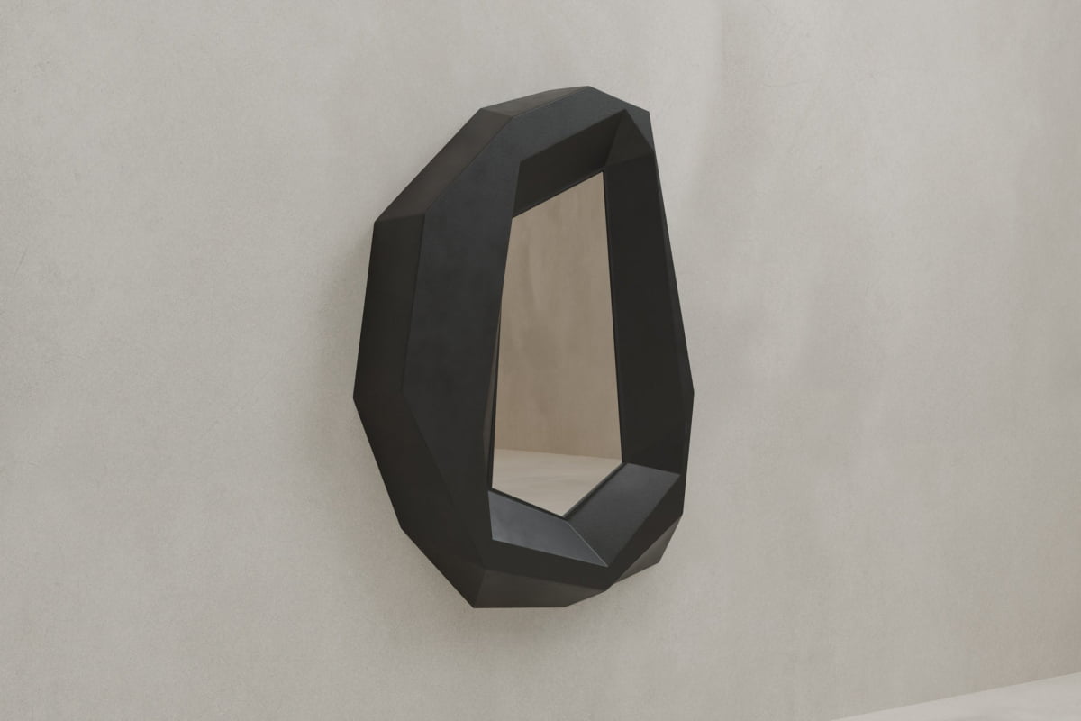 The Facet Mirror Large features a polygonal, black frame with angular edges, mounted on a light gray wall. Its irregular geometric shape adds modern sophistication and sculptural appeal to any space.