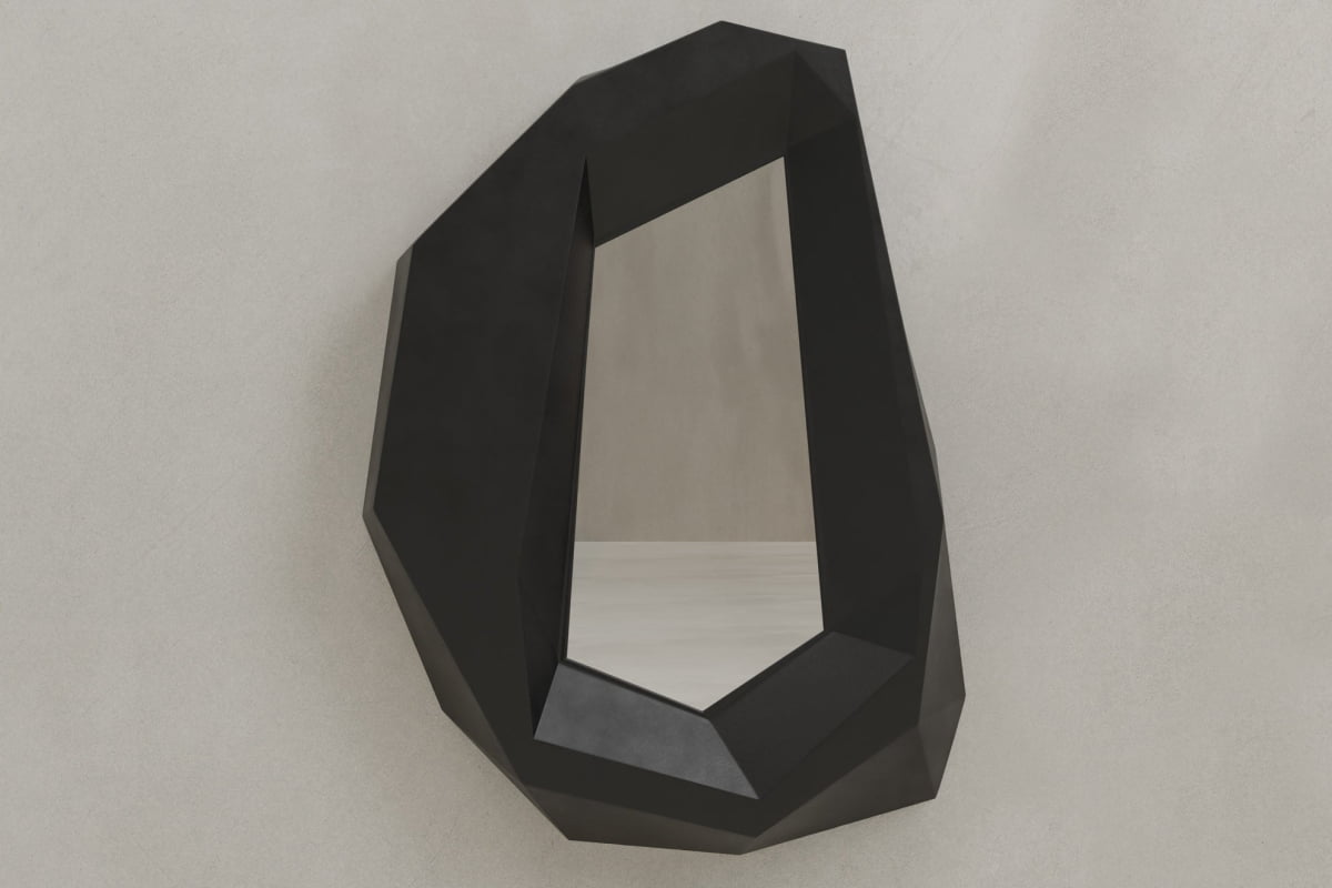 The Facet Mirror Large features an irregular black frame with sharp angles, channeling brutalist design and adding modern sophistication when mounted on a plain light-colored wall.