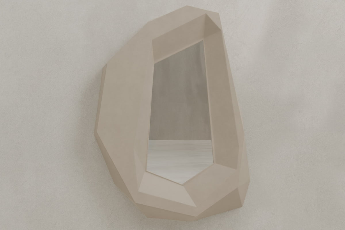The Facet Mirror Large features a geometric, angular beige frame with brutalist style, resembling a faceted gemstone, and is displayed on a textured light gray wall.