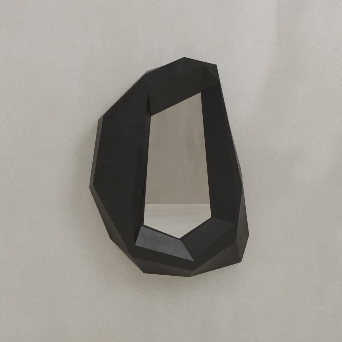 The Facet Mirror Small, with its wall-mounted irregular geometric black frame and angular edges, adds modern sophistication and a touch of brutalist design to any plain light-colored wall.