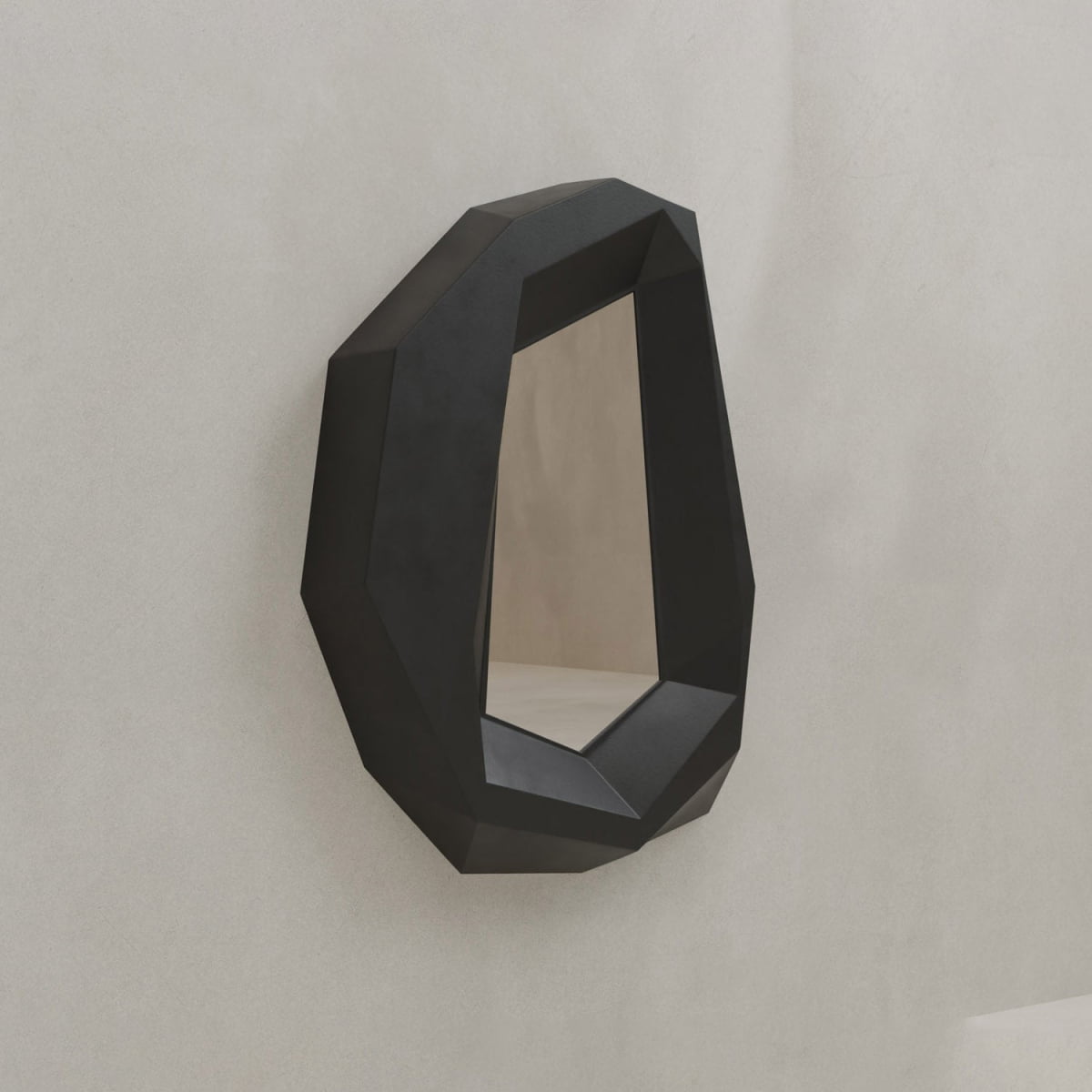 The Facet Mirror Small features a dark, sharp-edged frame and an irregular geometric form, mounted on a light wall to bring modern sophistication to any space.