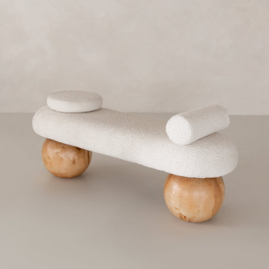 The Finchley Bench features a white textured seat, cylindrical backrest, round cushion, and two large wooden spherical legs—ideal for bringing modern sophistication to contemporary spaces.