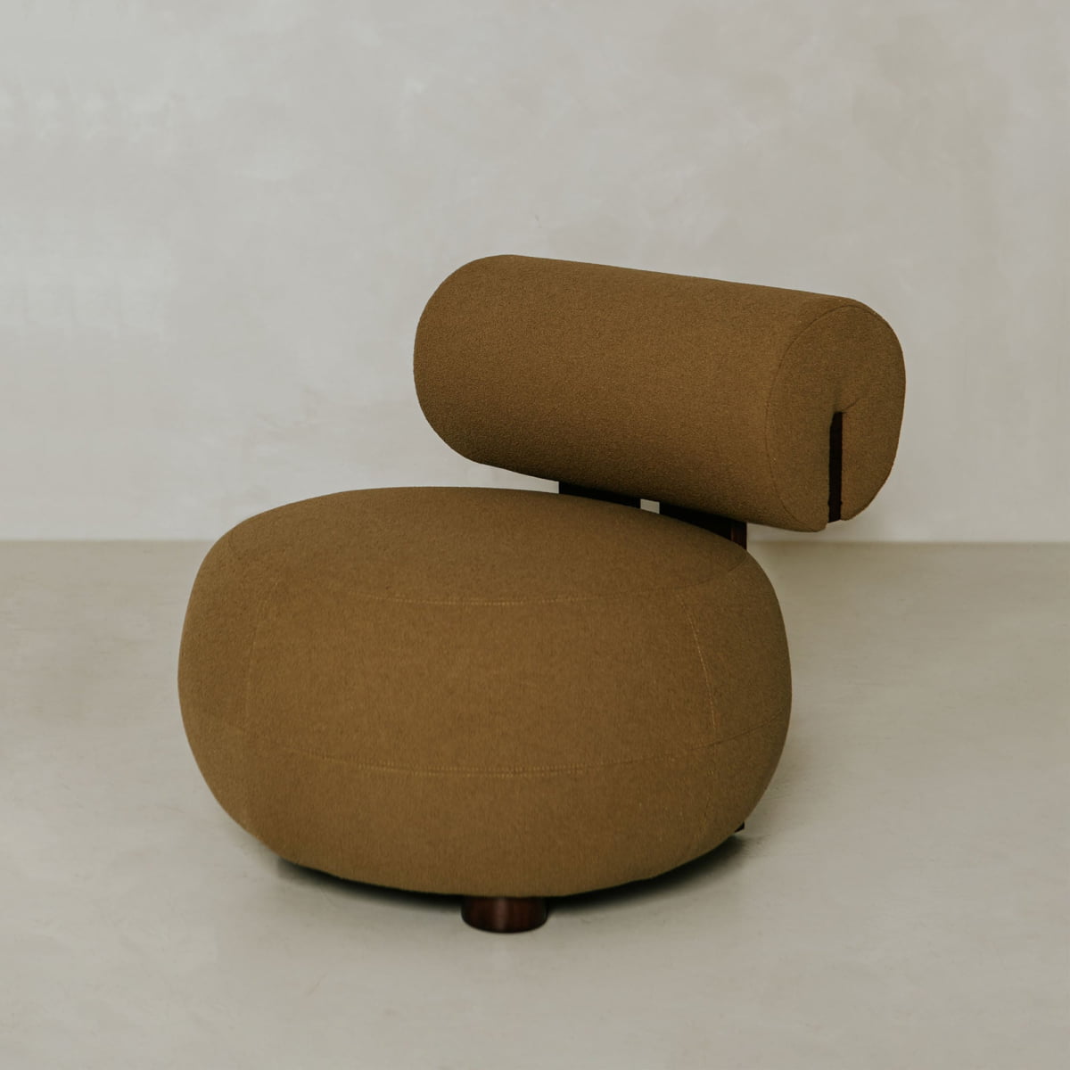 The Finchley Chair features a round, brown cushioned seat, sturdy solid legs, and a cylindrical backrest, all set against a plain light background.