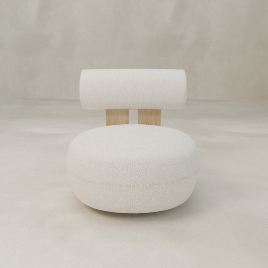 The Finchley Chair is a modern, minimalist piece featuring a round white cushioned seat, cylindrical white backrest, and two vertical wooden slats as supports, displayed against a plain, light-colored background.