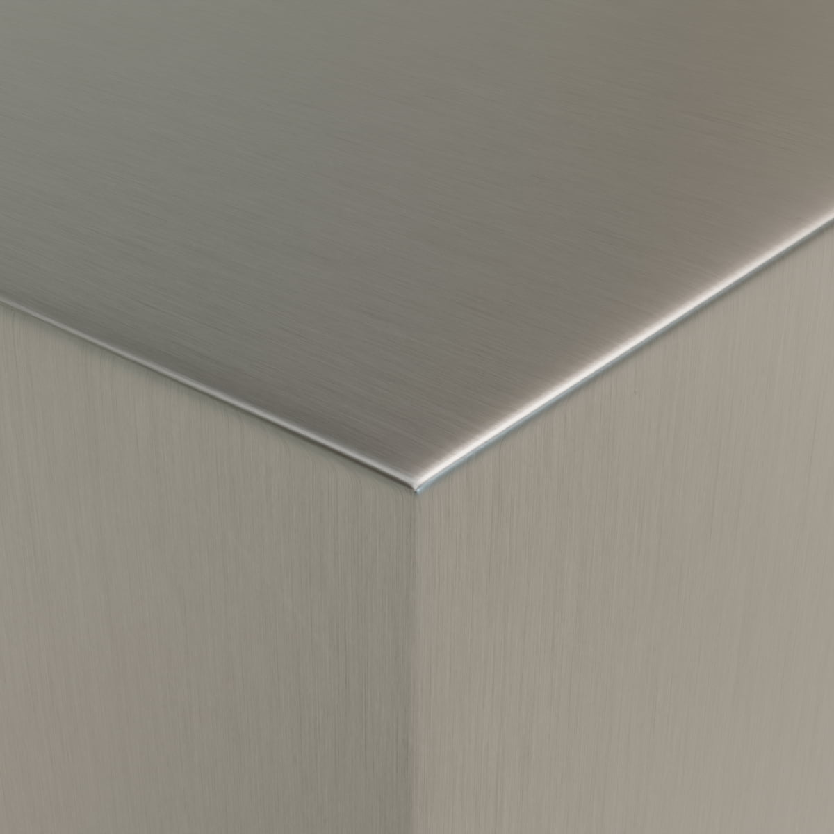 A close-up of the Forge Steel Large Rectangular Plinth’s corner highlights its brushed stainless steel surface, smooth clean lines, and reflective metallic finish for a modern industrial look.