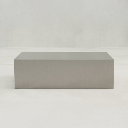 The Forge Steel Large Rectangular Plinth, featuring a minimalist modern design, sits on a smooth light-colored floor against a plain light-gray wall.