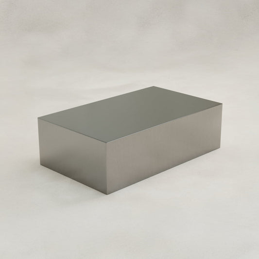 The Forge Steel Large Rectangular Plinth features a plain, shiny steel finish and smooth edges, displayed on a light, neutral background to highlight its modern design.