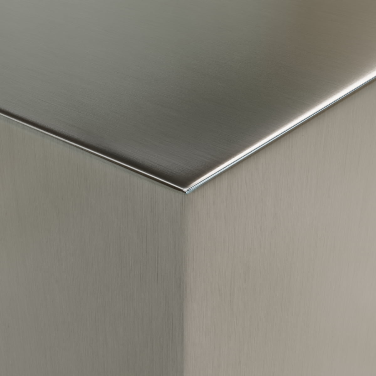 Close-up of the sharp corner of the Forge Steel Large Square Plinth reveals a clean, smooth brushed metal surface with a subtle sheen and reflective quality, emphasizing its modern design.