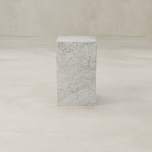 The Griselle Marble Plinth - Tall, featuring rectangular form and gray veining, stands on a smooth neutral floor against a plain wall—an ideal choice for elegant interior decor.