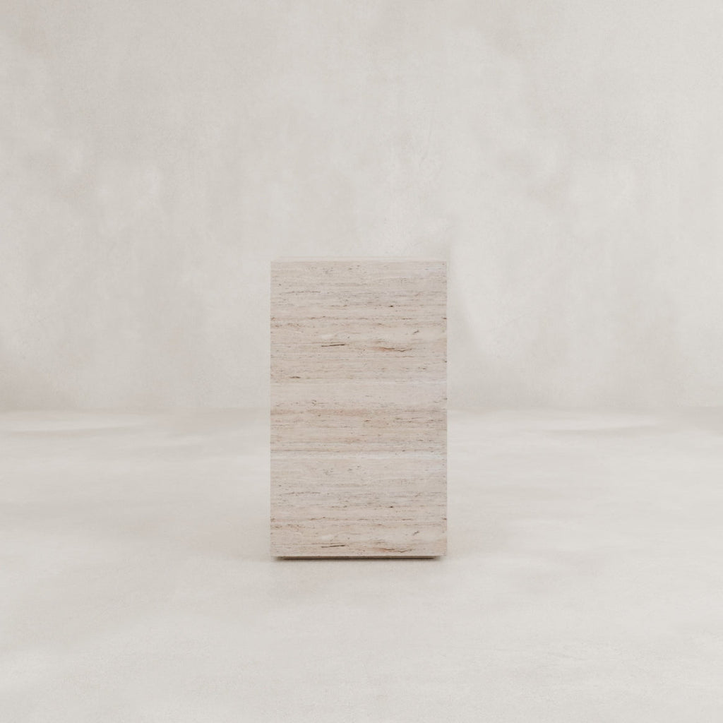 The Haven Travertine Plinth, crafted from natural travertine stone, stands elegantly in a softly lit, neutral space with a smooth background—perfect for minimalist and sophisticated decor.