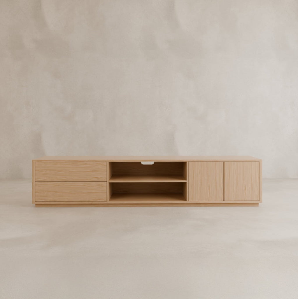 The Indre Media Console is a minimalist wooden TV stand with a natural finish, featuring three left drawers, two open center shelves, and a right cabinet—ideal for modern spaces against a light background.