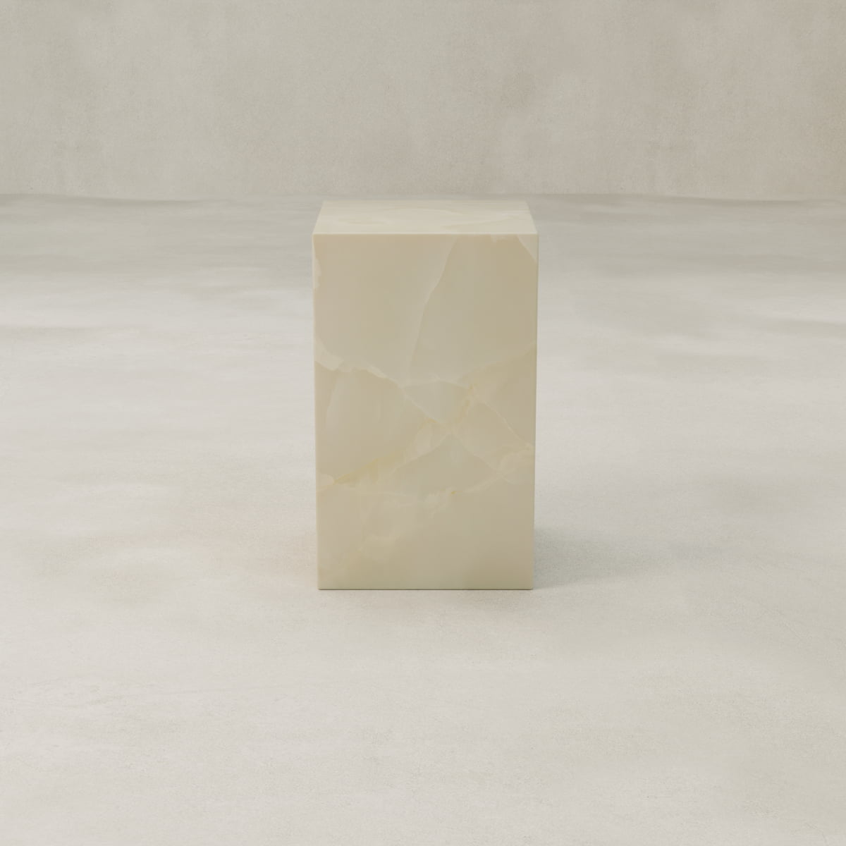 The Lunelle Onyx Tall Tower Plinth, featuring a smooth, polished milky surface, stands out as a sculptural centerpiece on a light textured floor against a neutral background.