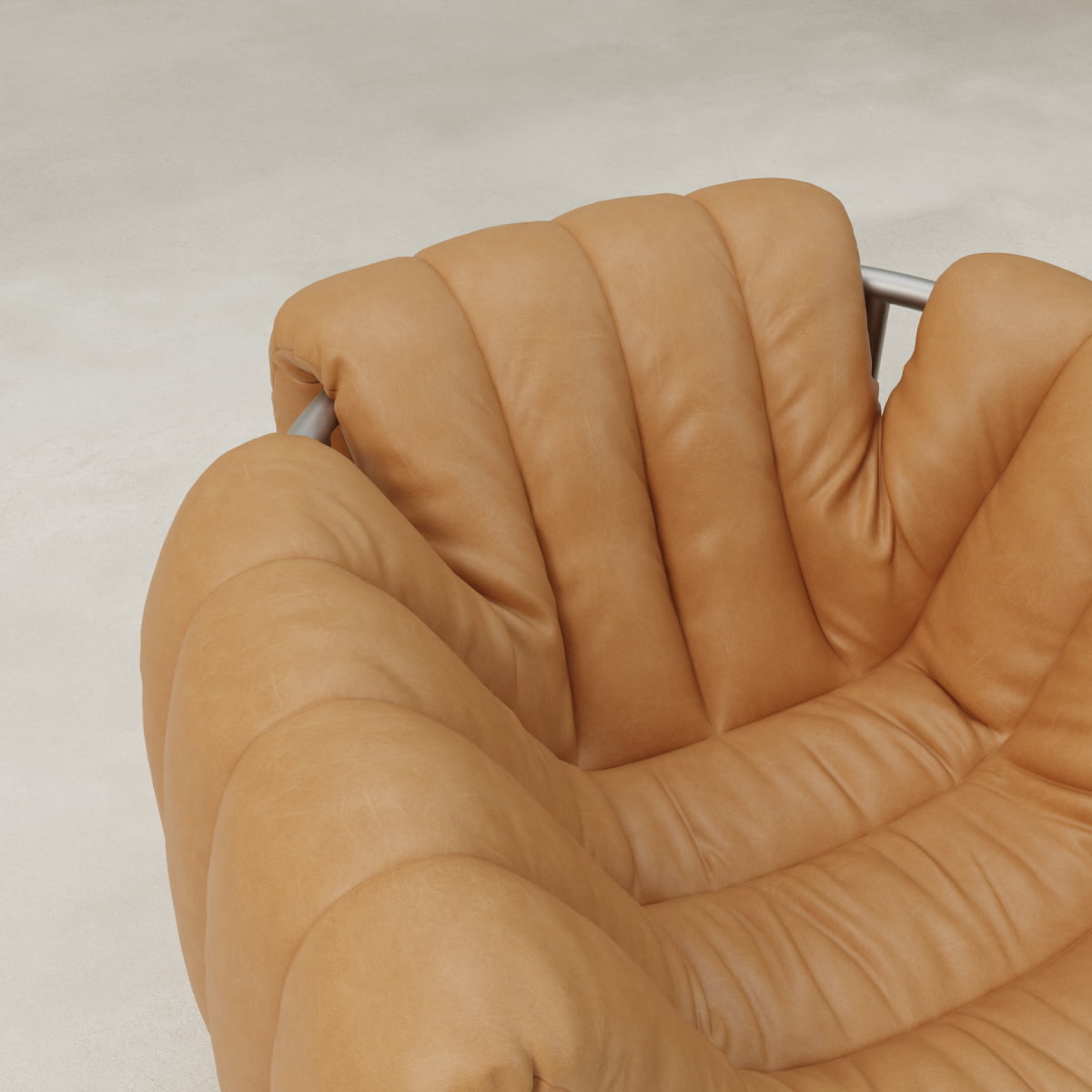 Close-up of the Mallow Chair, showcasing plush tan leather upholstery, deep channel tufting, and a sculptural tubular frame against a smooth, light-colored background.