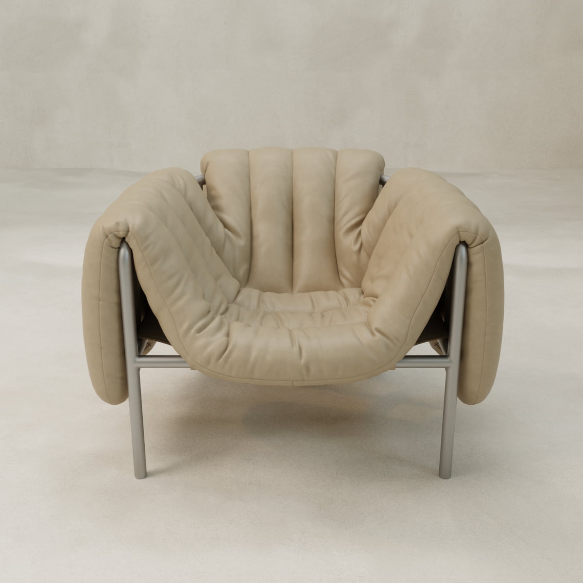 The Mallow Chair features deep channeled tufting on a plush beige cushion and a sturdy tubular silver frame, set against a light neutral background.