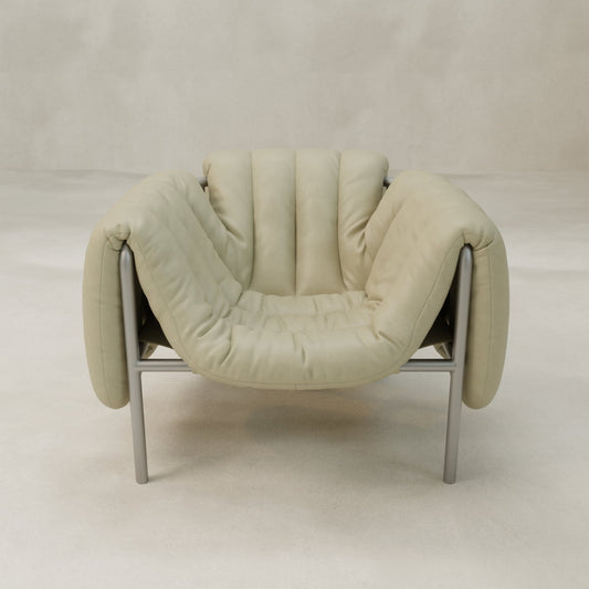 The Mallow Chair features a soft, padded beige cushion over a sculptural tubular frame, showcased against a simple, light background.