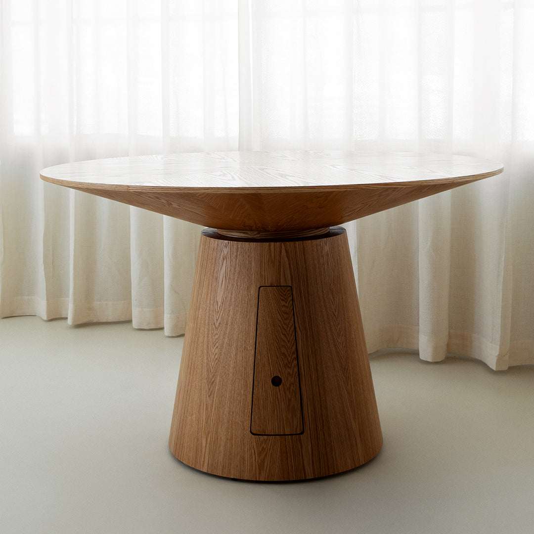 The Nola + Elsa Dining Set features a modern round wood table with a wide, flat top and conical base, complemented by woven seat chairs. Perfect for minimalist rooms with light curtains and flooring.
