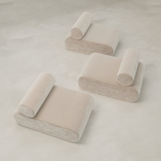 Three minimalist, beige Nuage Modular Lounge Chairs with cylindrical backrests sit on a light, textured surface. Their sculptural design and plush look create a soft, modern aesthetic when viewed from above.