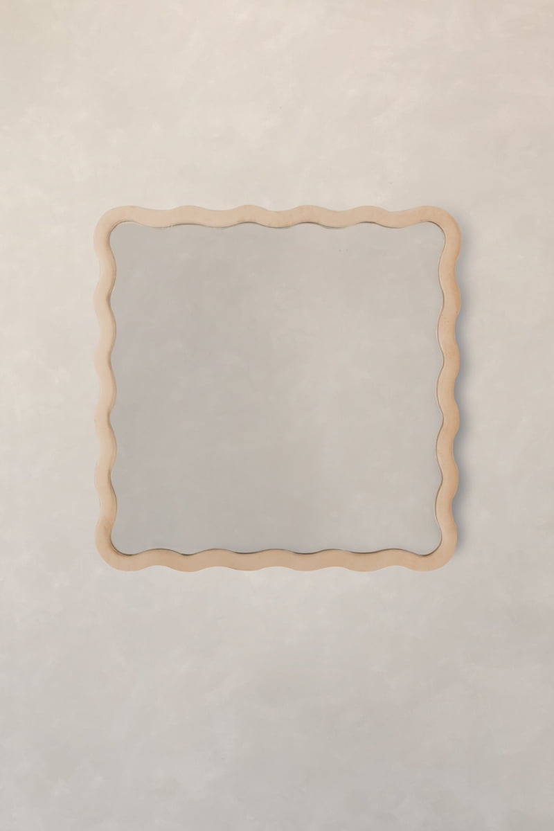 The Onde Mirror Small features a rectangular shape and a wavy light wooden frame, ideal for modern interiors when hung on a pale, textured wall.
